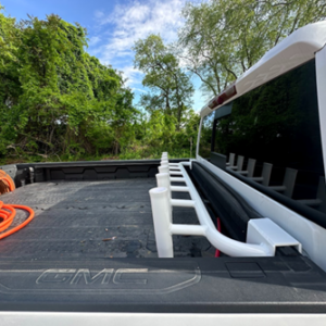 Custom no-drill truck bed fishing rod holder installed in a pickup truck bed, featuring multiple vertical rod slots and a removable slide-on design.